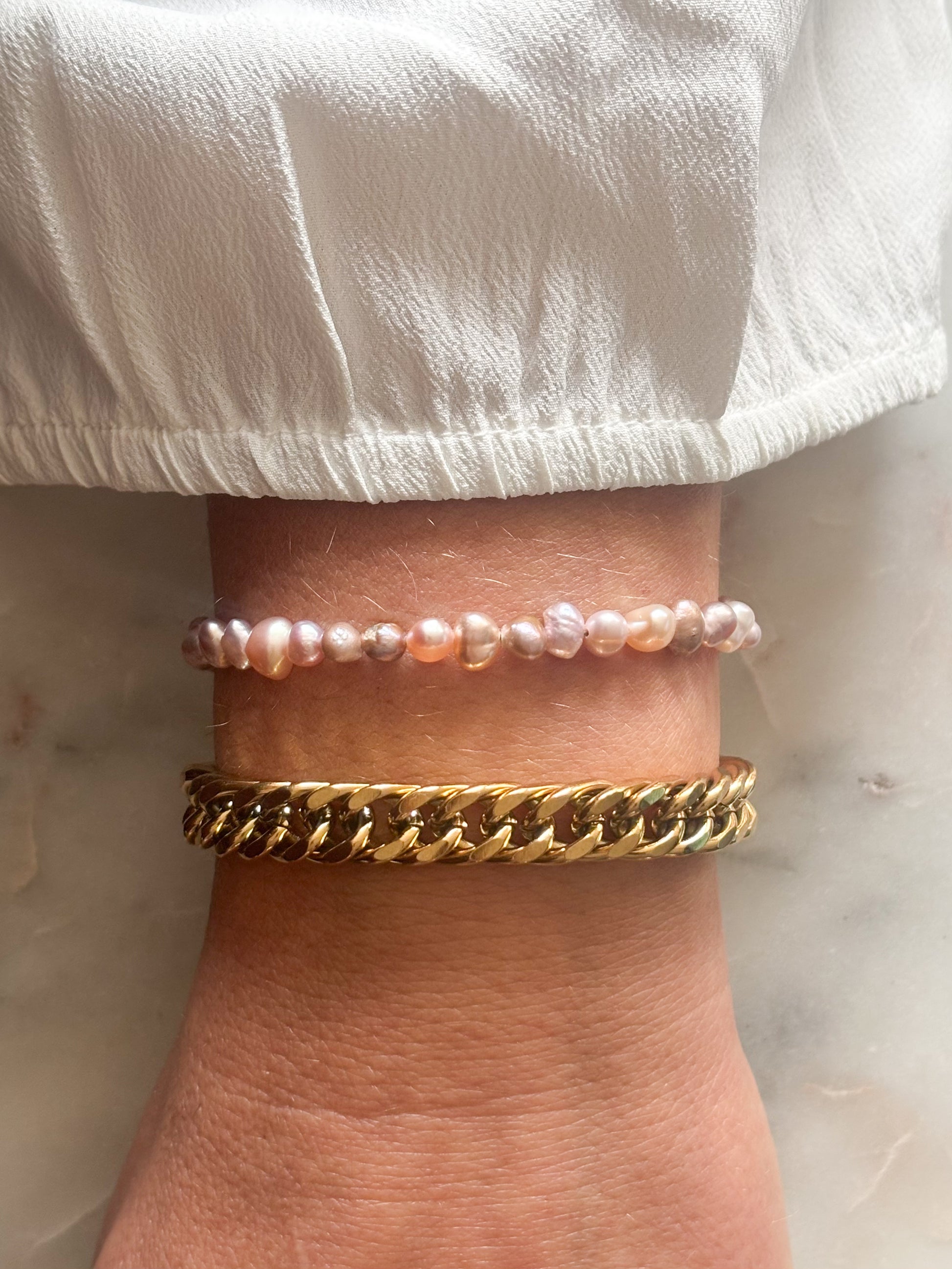 vrouwen pols met parel armband en schakel armband