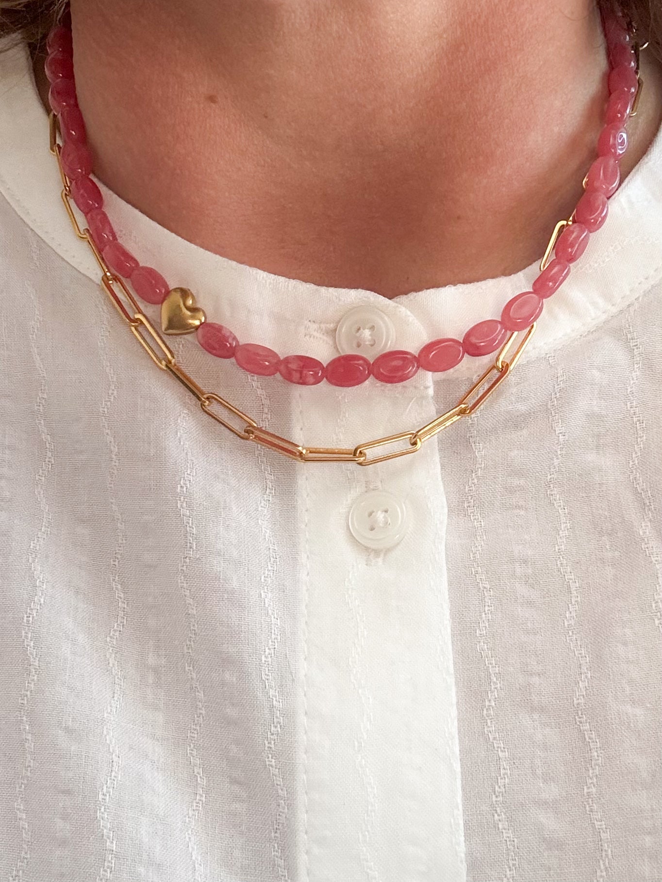 Vrouw met roze kralen ketting en gouden schakel